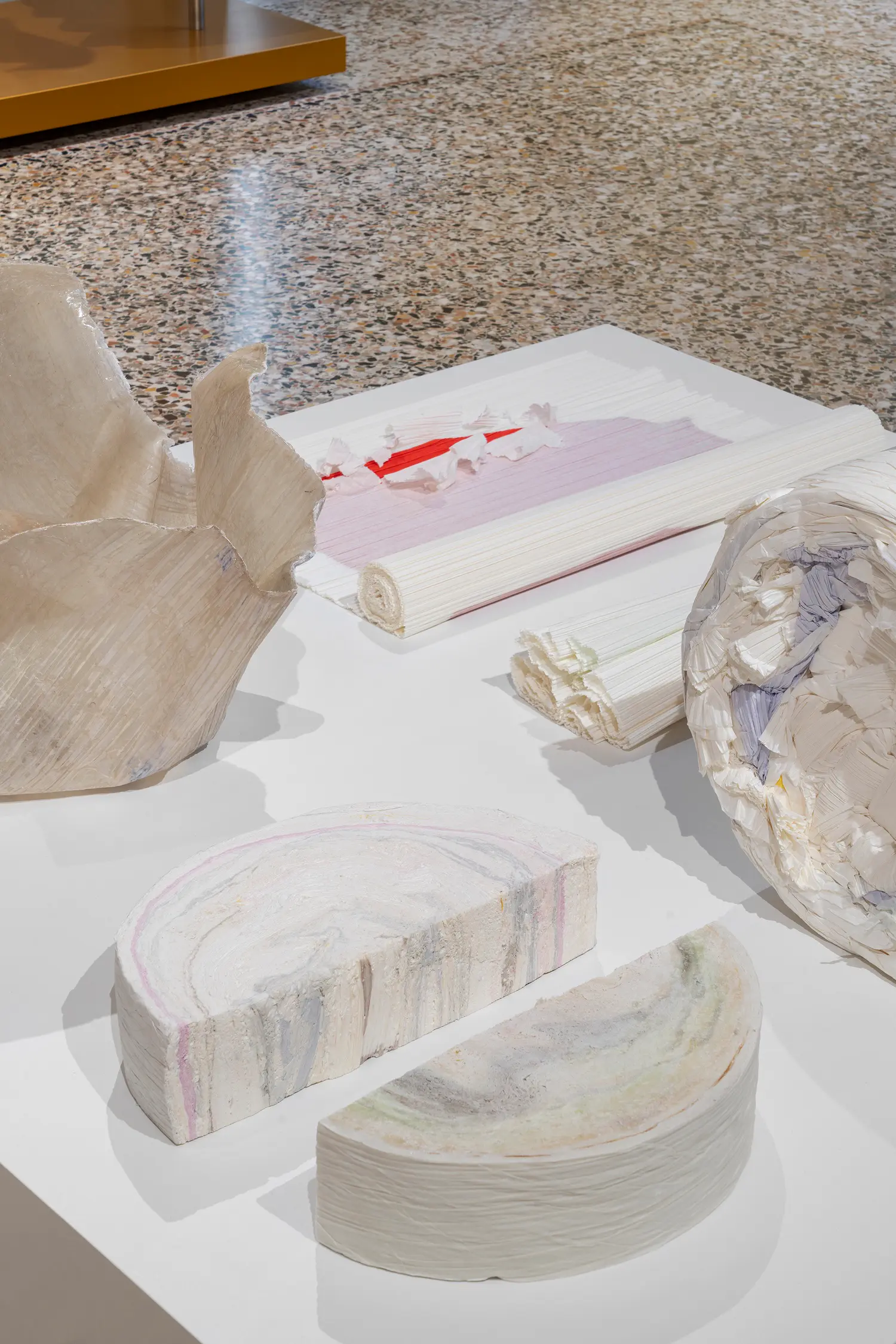 Close-up of material samples including rolls of pleated paper and cross-sections showing colorful marbled rings.