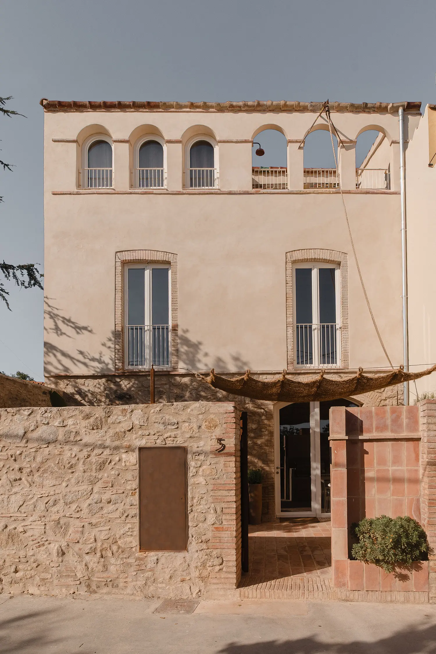 The exterior facade of La Fusteria featuring arched openings and a stone walled courtyard in Alt Empordà.
