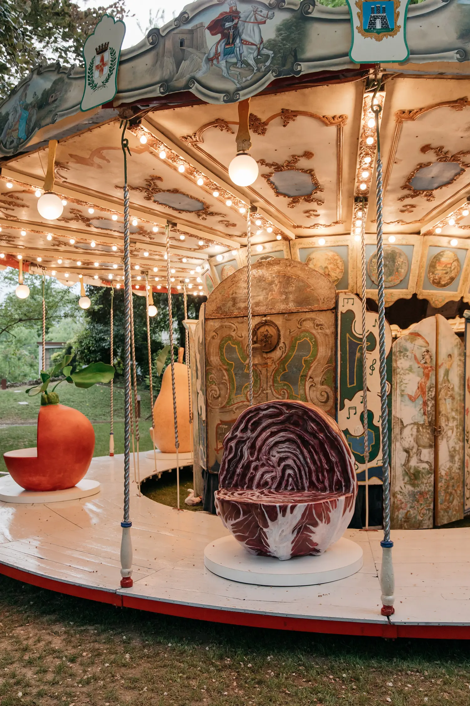 Oversized radicchio and carrot seats on the wooden platform of the antique carousel.