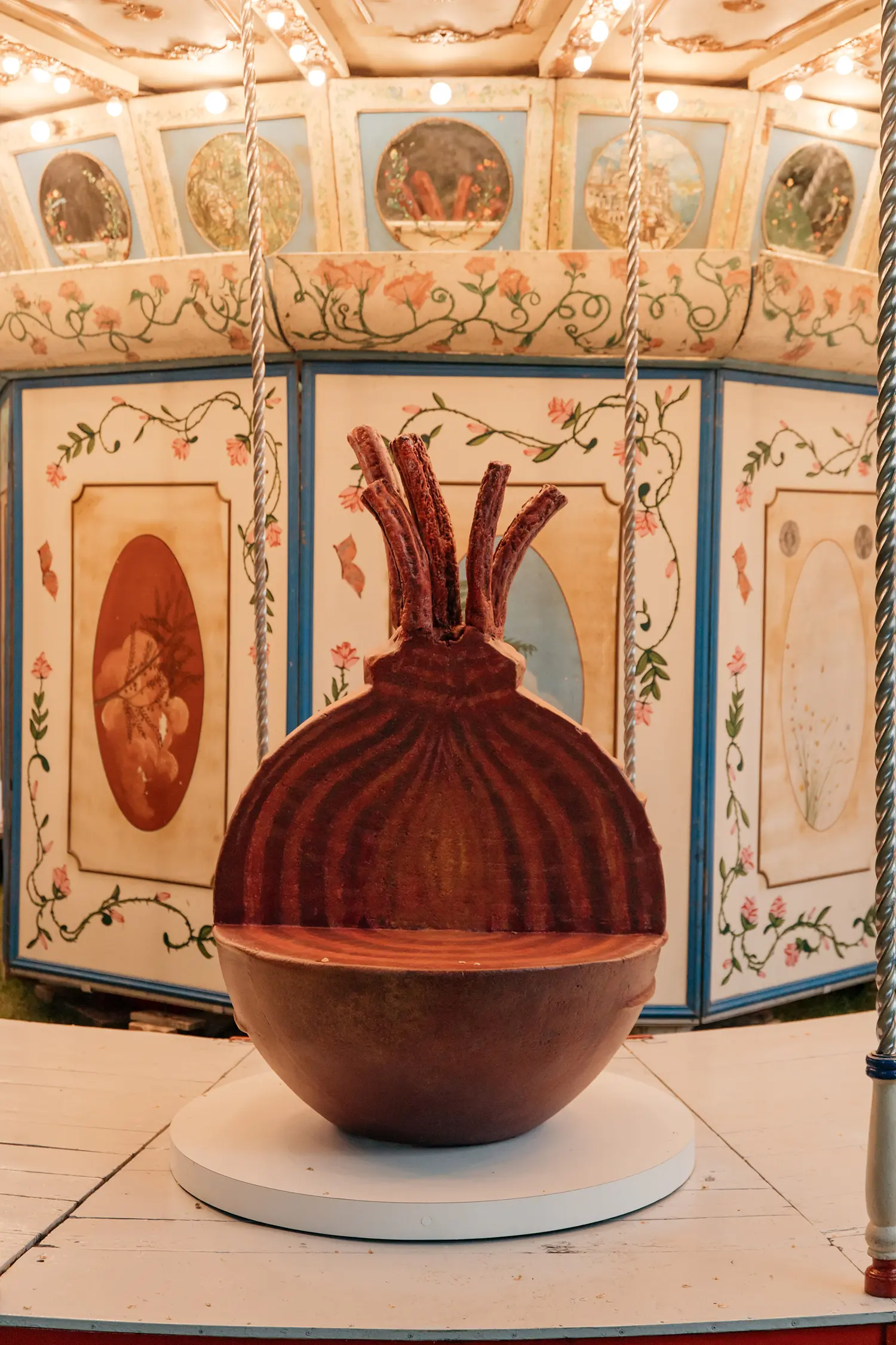 A large beetroot or onion sculpture with vertical stalks used as a seat on the carousel.