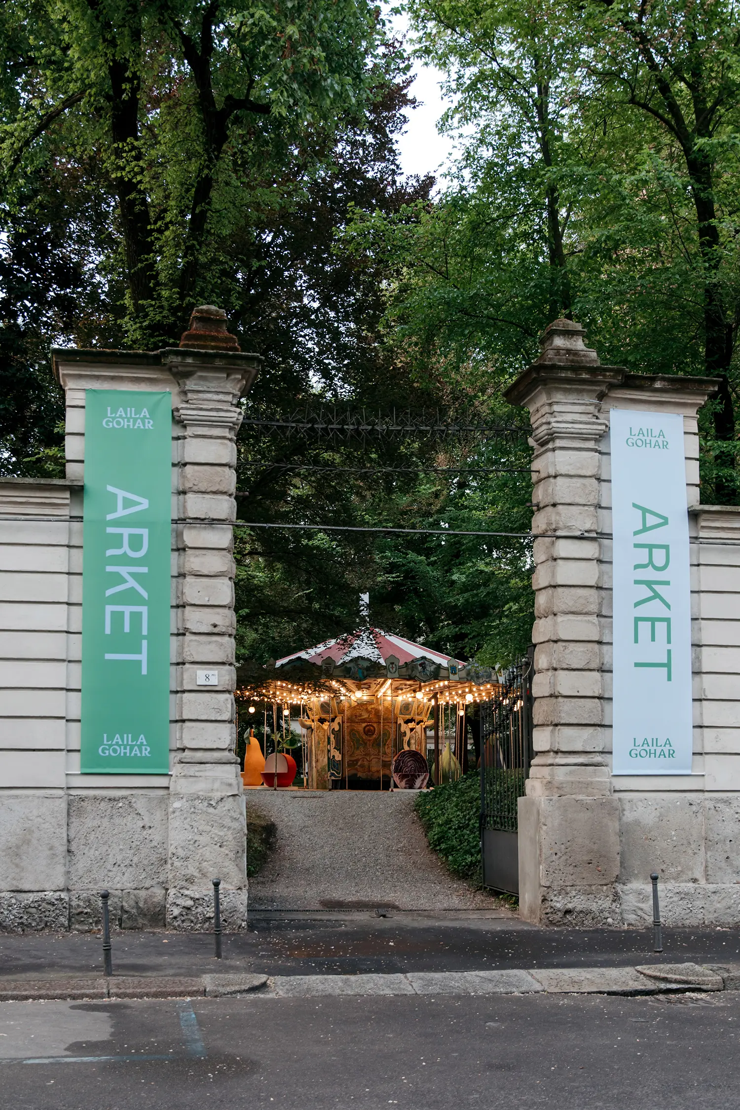 The stone entrance of Giardino delle Arti with green and white ARKET x Laila Gohar banners.