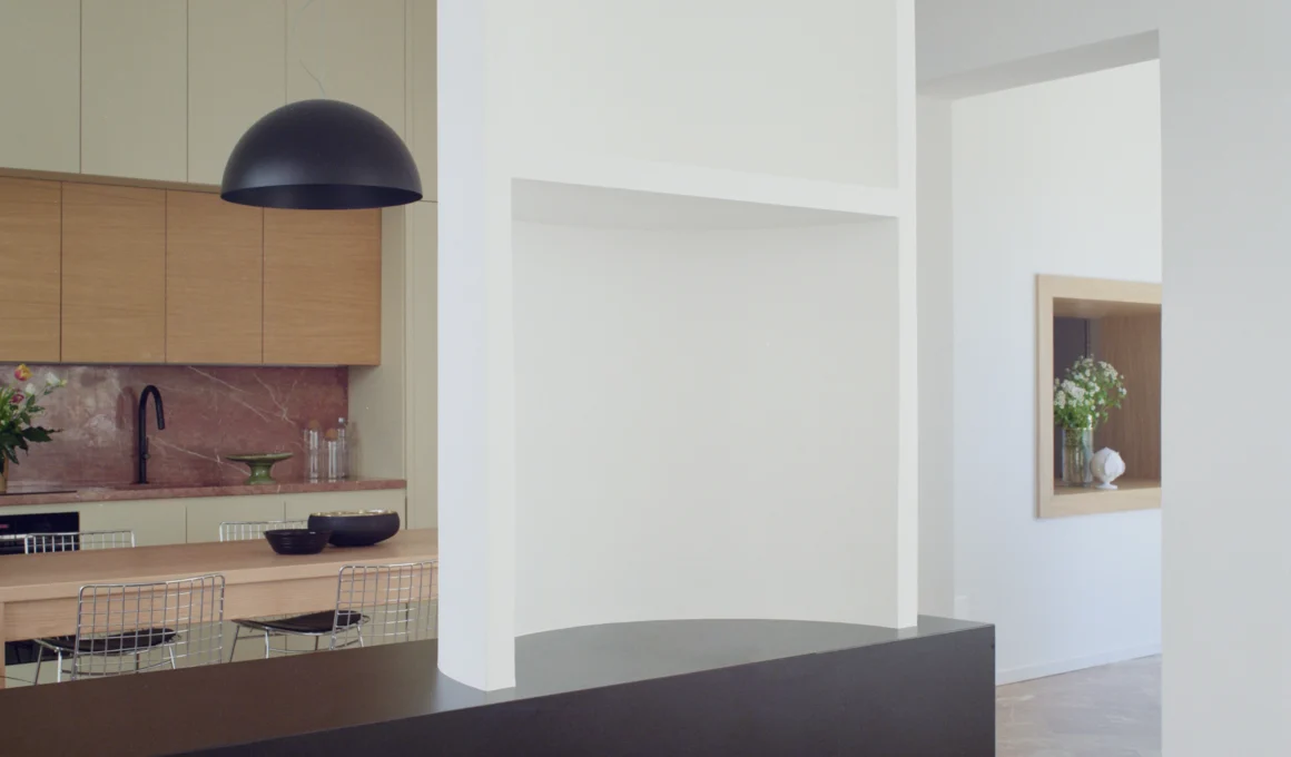Minimalist interior view of Lèvanzo house showing a white semi-column and Rosa del Garda marble kitchen backsplash.
