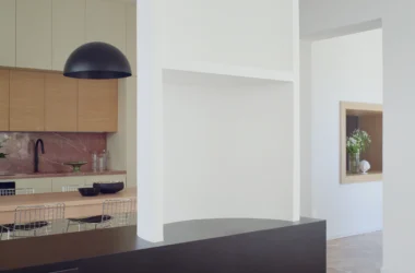 Minimalist interior view of Lèvanzo house showing a white semi-column and Rosa del Garda marble kitchen backsplash.