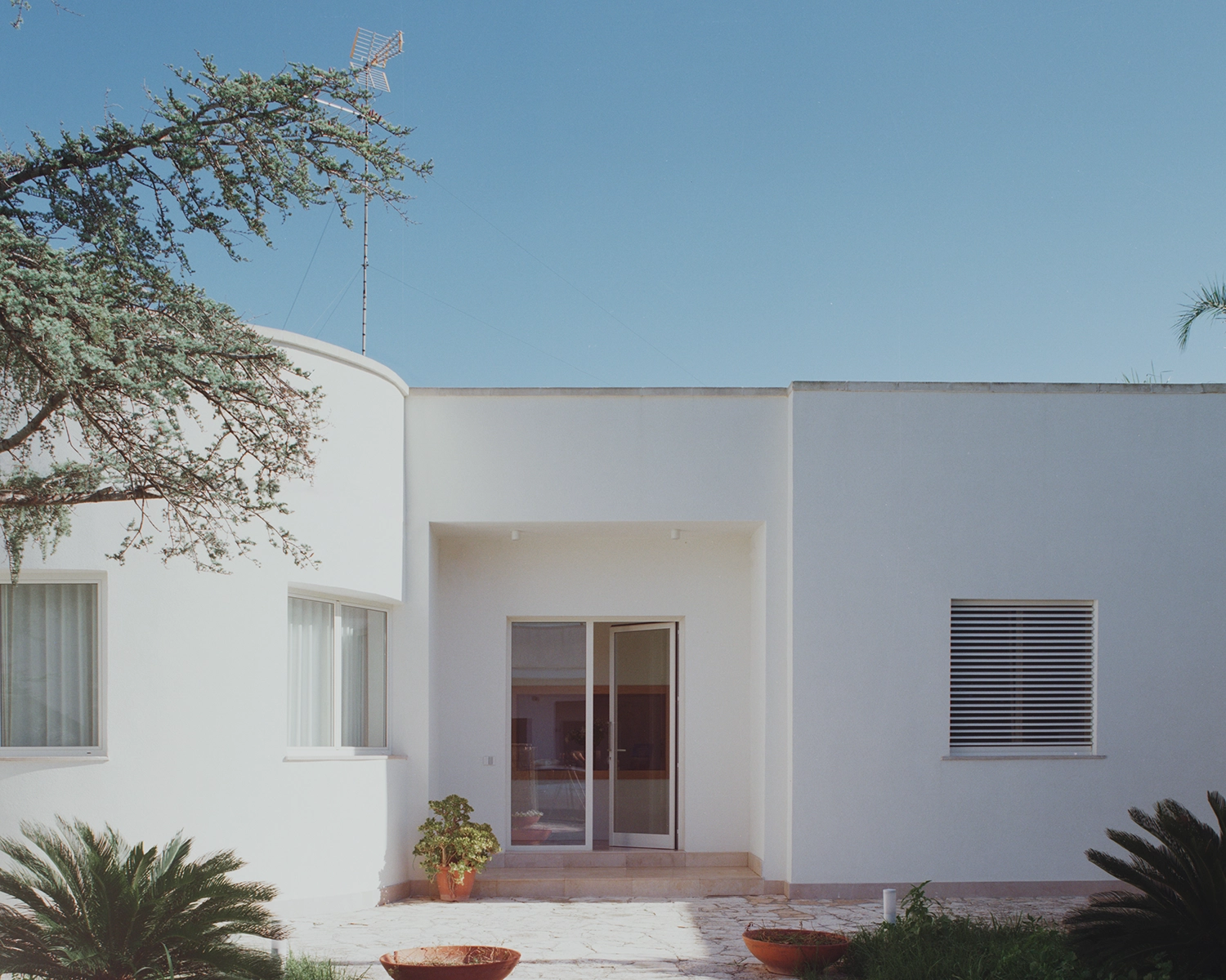Front exterior of Lèvanzo house by Margine Studio featuring white volumes and a minimalist entrance.
