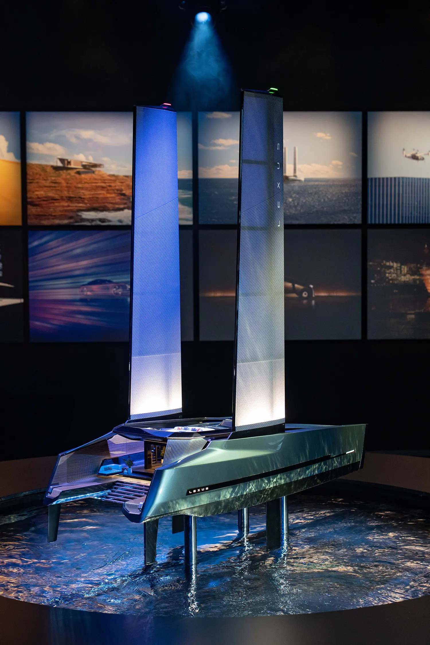 A miniature model of a futuristic luxury foiling catamaran floating in a pool of water at the Lexus exhibition.