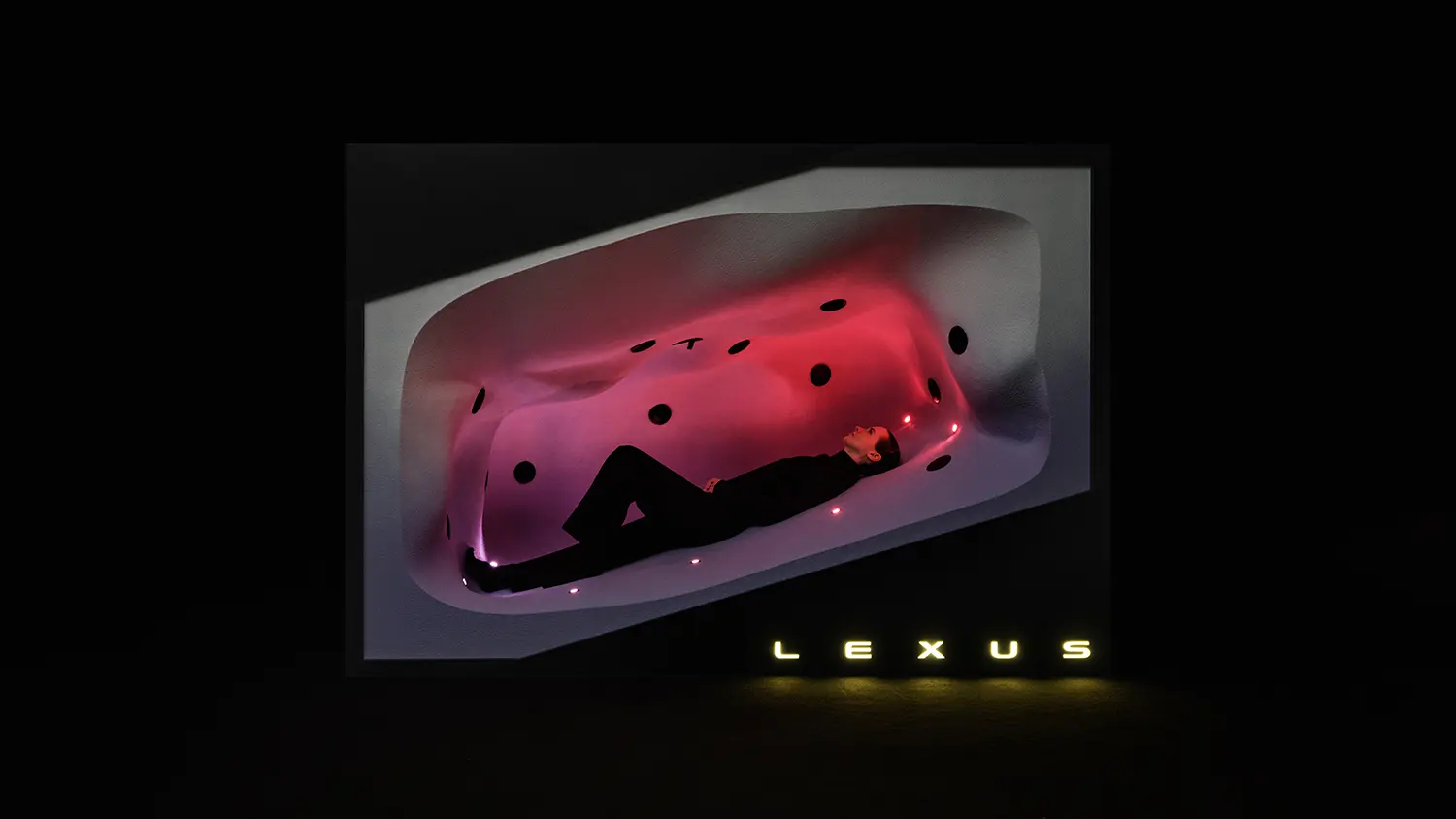 A person lying down inside a white, pod-like organic structure glowing with red internal lights.
