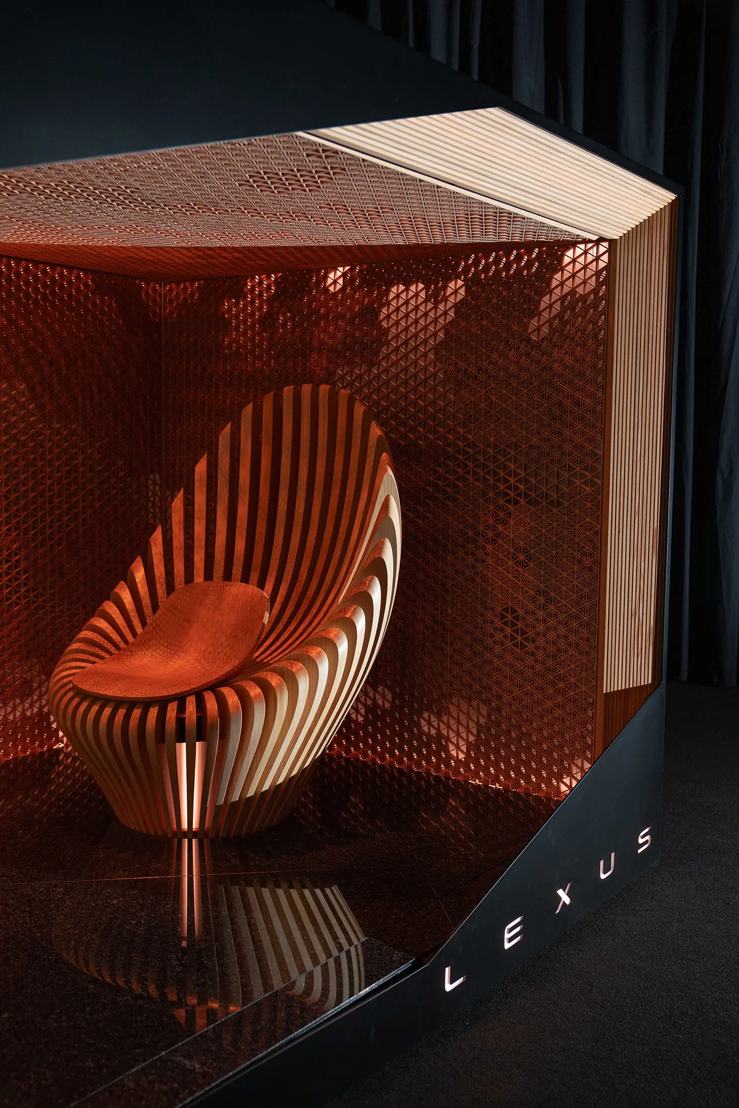 Detail shot of a fan-shaped wooden chair with a leather seat inside a textured copper-finished alcove.