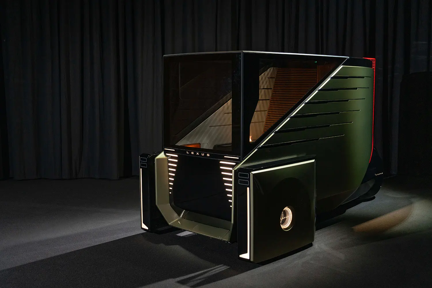 Side profile of the Lexus LS Micro Concept, a compact urban luxury vehicle with green metallic panels and glass cabin.