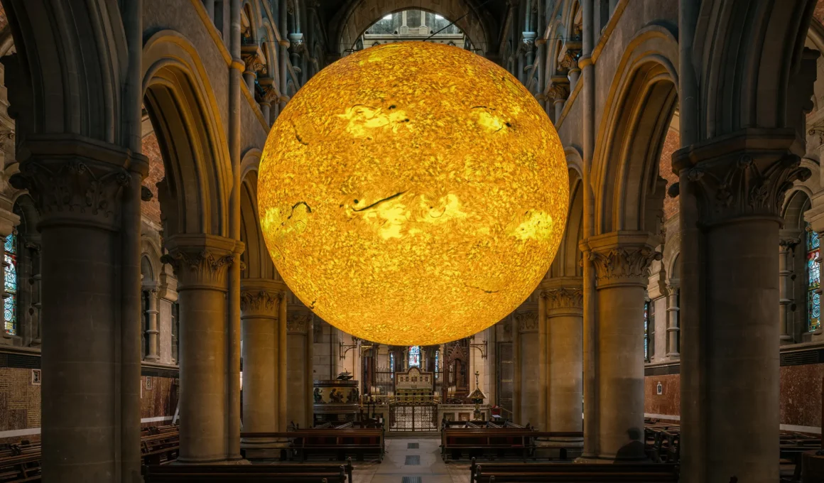 Helios sun sculpture by Luke Jerram suspended in a gothic cathedral nave.