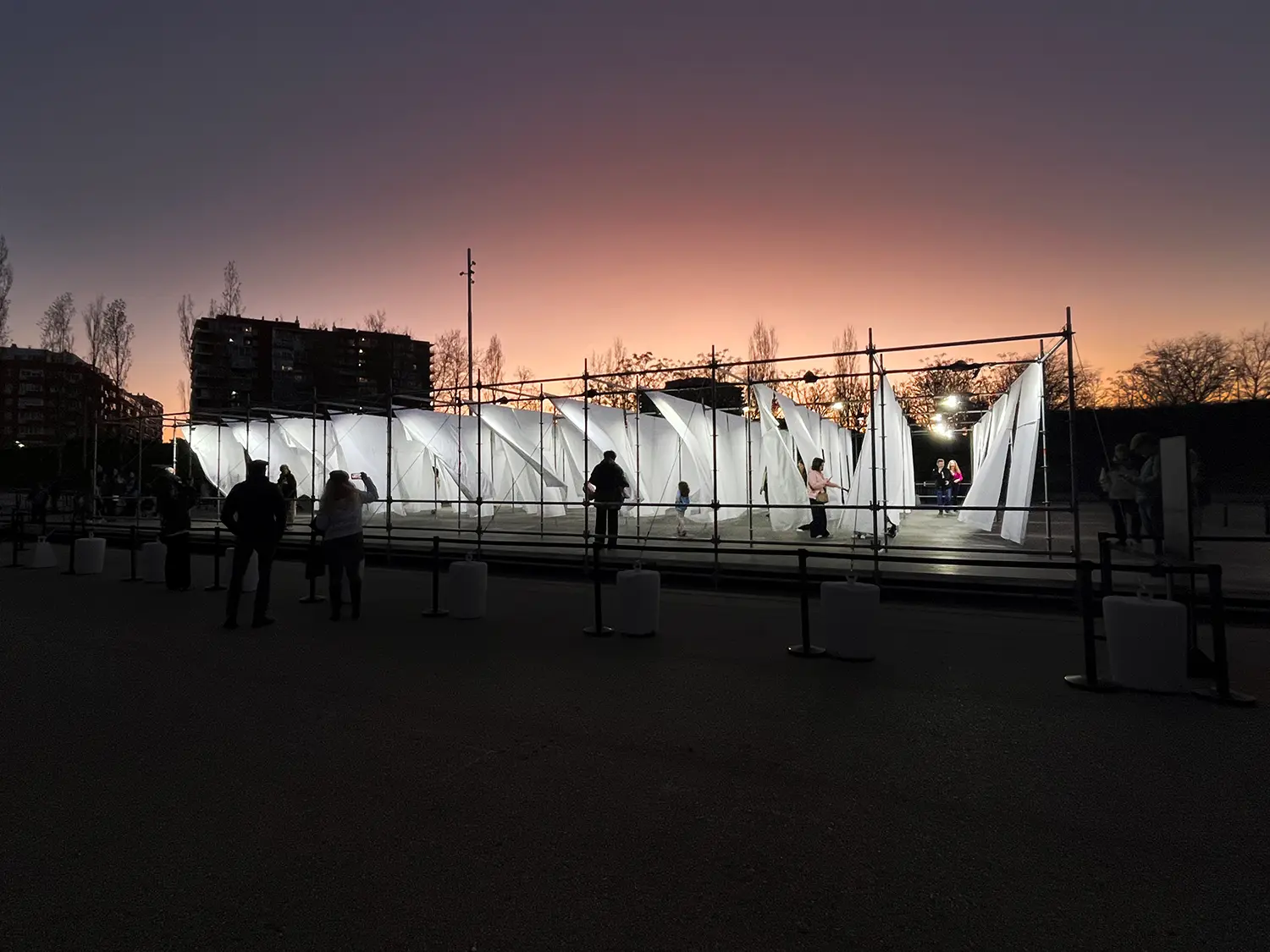 Wide shot of the glowing Hanging Landscapes installation at dusk with a purple and orange sunset sky.