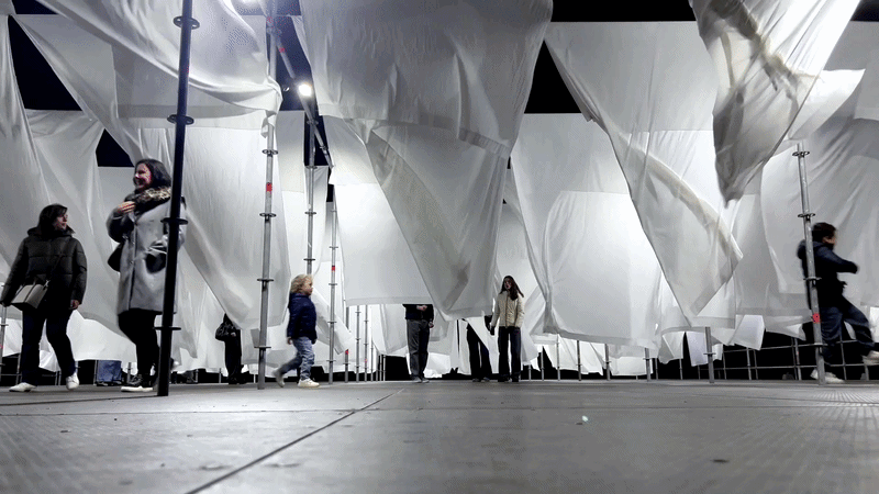 Animated GIF of children and adults running through the rows of moving white sheets.