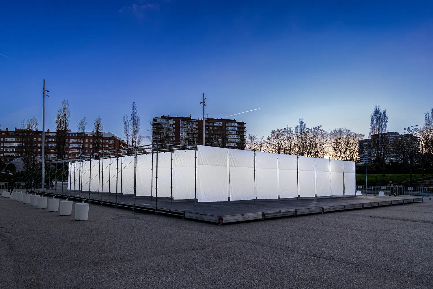 Exterior wide shot of the rectangular scaffolding installation on a paved plaza during blue hour.