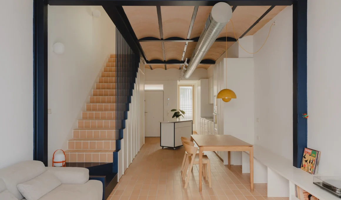 Open-plan living area with vaulted terracotta ceiling and blue steel structure.