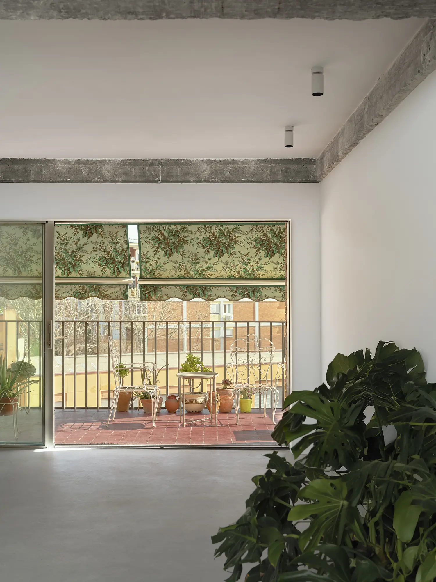 Interior view of a living room looking out onto a terrace with floral patterned awnings.