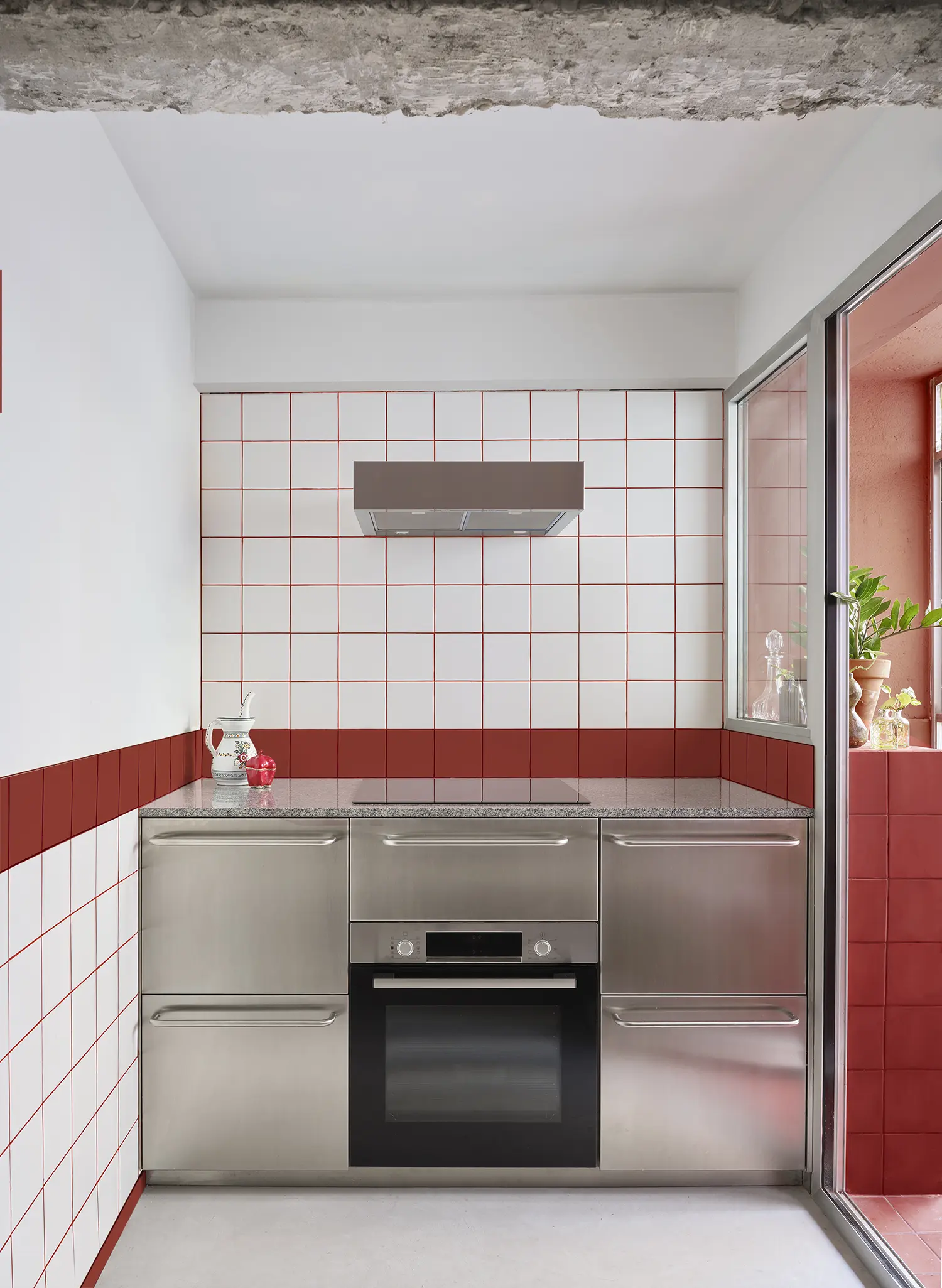 Modern kitchen workspace with stainless steel appliances and a white and red tiled backsplash.