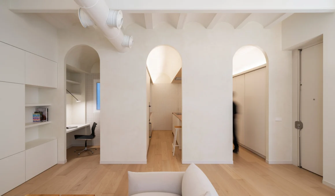 View from a living room toward three arched openings leading to a study, kitchen, and hallway in a Valencia apartment.