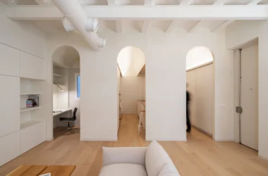 View from a living room toward three arched openings leading to a study, kitchen, and hallway in a Valencia apartment.