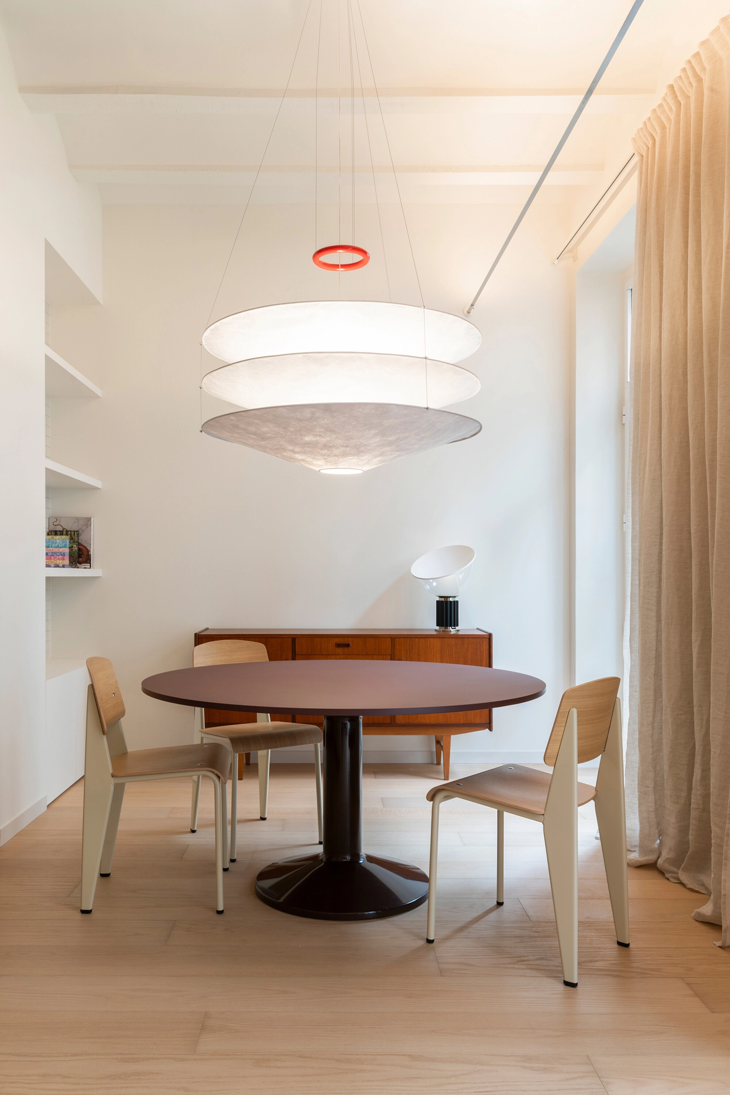 Dining area with a round dark wood table, vintage-style chairs, and a large tiered pendant light.