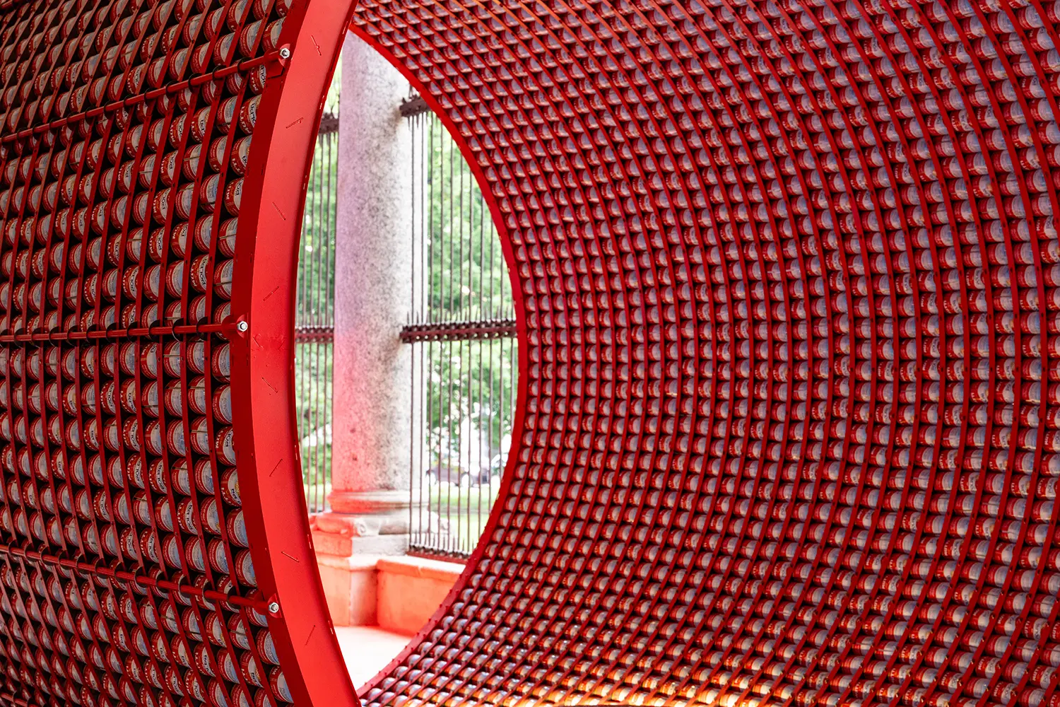 Extreme close-up of a red metal frame holding rows of Mutti tomato cans in a curved formation.