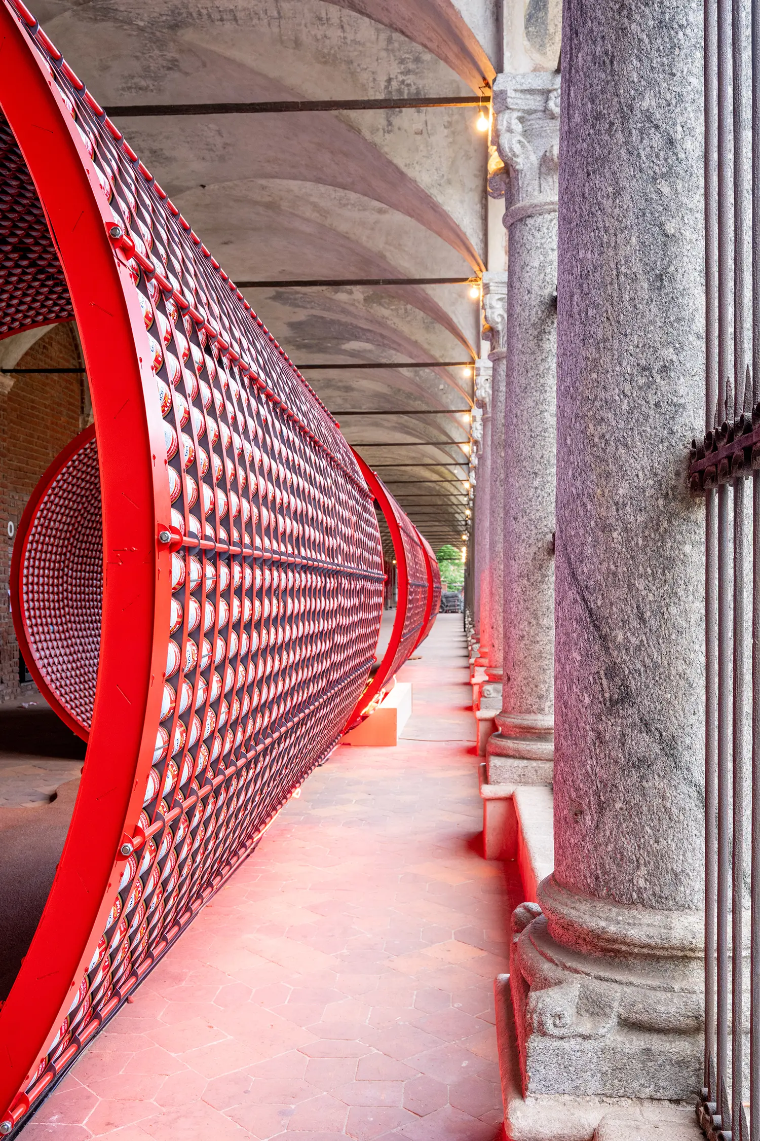Vertical shot of the exterior of a red can cylinder against the backdrop of classical stone columns.