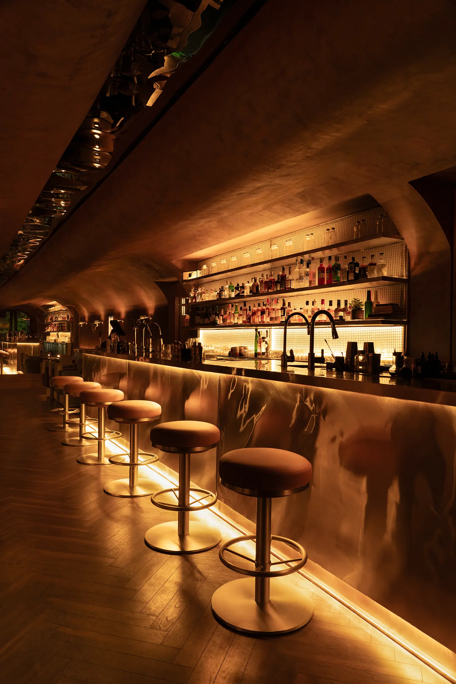 Close-up of stainless steel bar stools and a reflective metal counter at No Vacancy bar in Delhi.