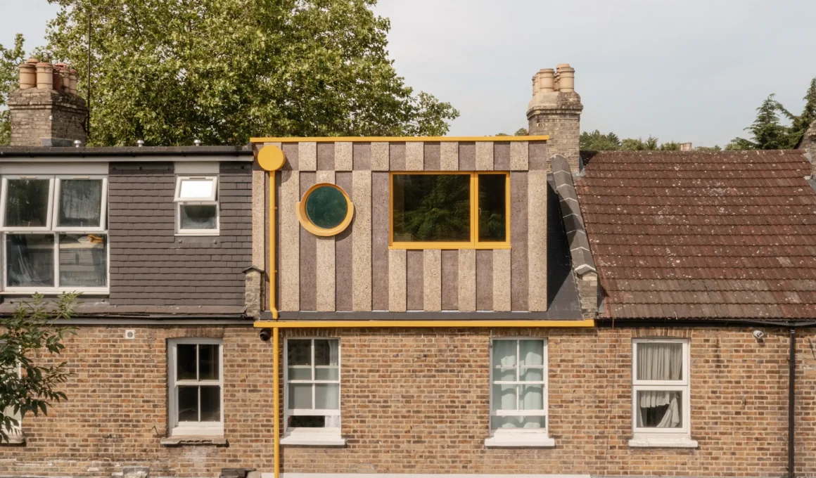 Exterior view of a Victorian terrace roof featuring a multi-tonal cork loft extension with yellow circular and rectangular windows.