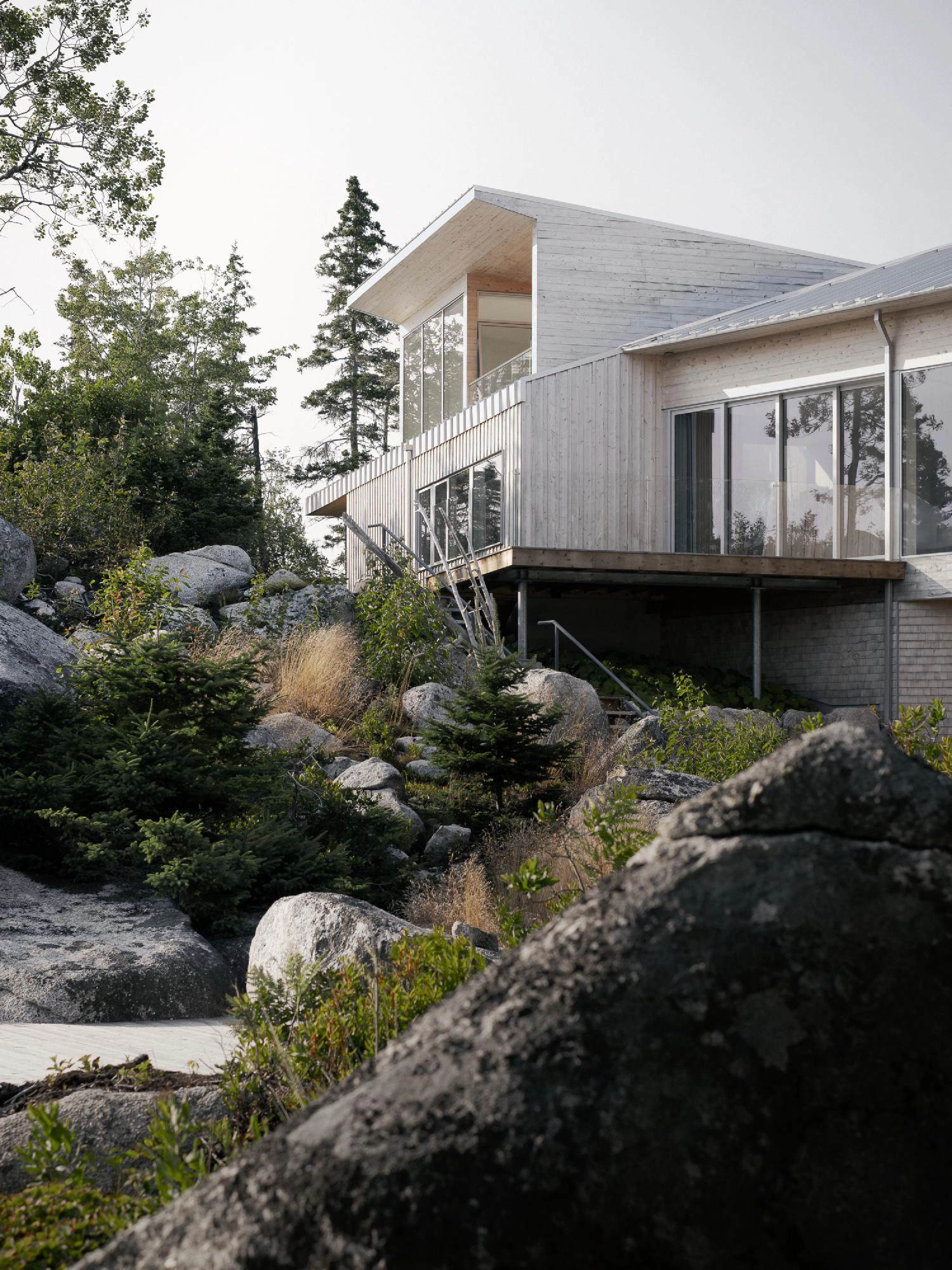 Side view of the East River Residence showing the lifted roofline and a cantilevered wooden deck.