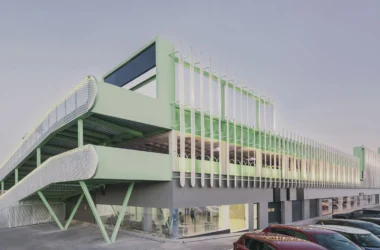 Exterior view of Leganés Auto Center featuring a mint green ramp and perforated metal facade in Madrid.