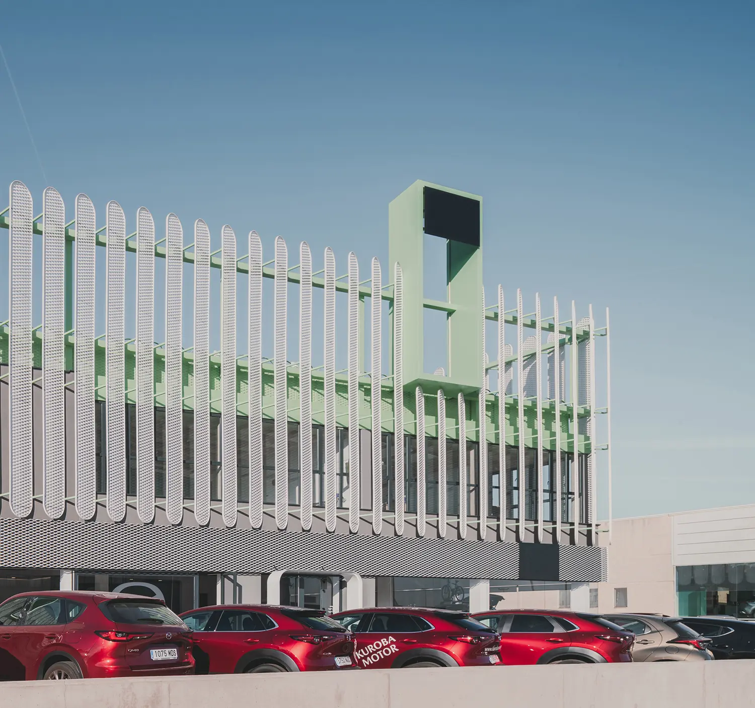 Close-up of the rhythmic mint green vertical slats on the facade of the Leganés Auto Center.