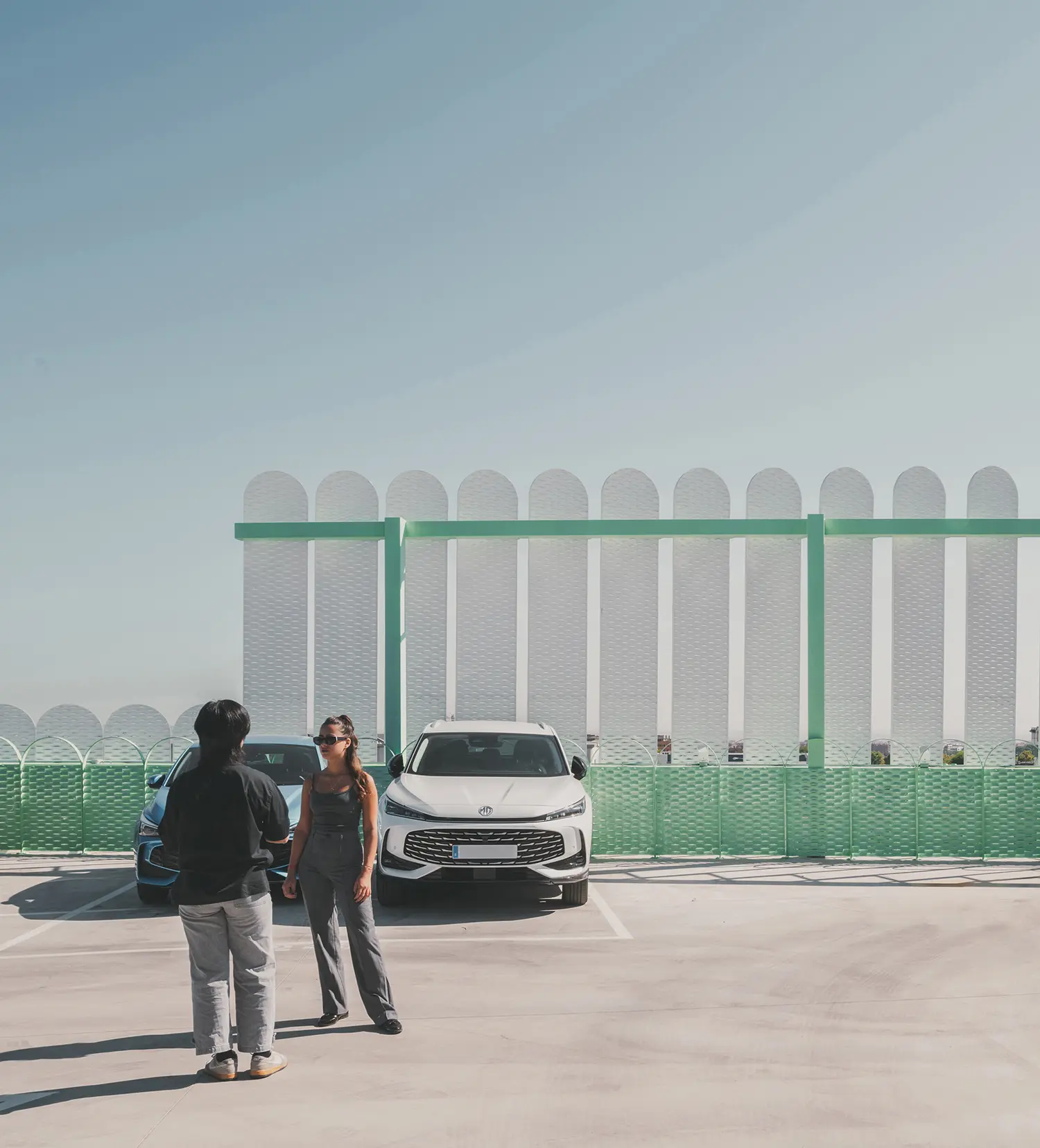 Rooftop view of Leganés Auto Center with white cars and decorative green fencing.