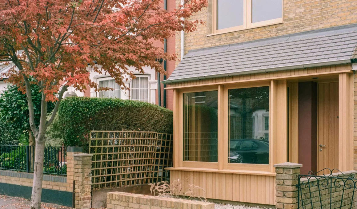Exterior view of a Victorian house in Walthamstow featuring a contemporary Red Grandis timber porch and large glass windows.