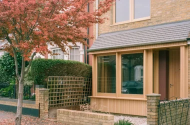 Exterior view of a Victorian house in Walthamstow featuring a contemporary Red Grandis timber porch and large glass windows.