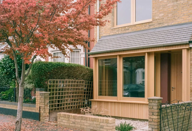 Exterior view of a Victorian house in Walthamstow featuring a contemporary Red Grandis timber porch and large glass windows.