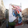 Wide street-level view of PichiAvo's Athena mural on Pallados Street in Athens.
