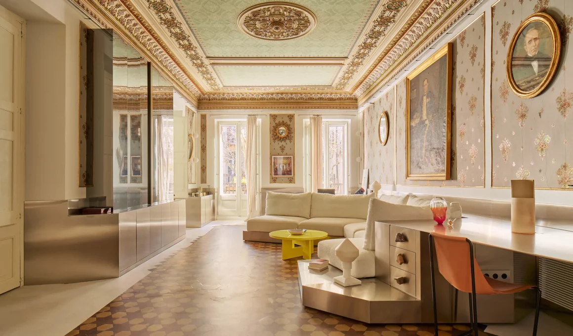 Wide view of a historic room featuring a polychrome ceiling, stainless steel plinth, and original terracotta floors.