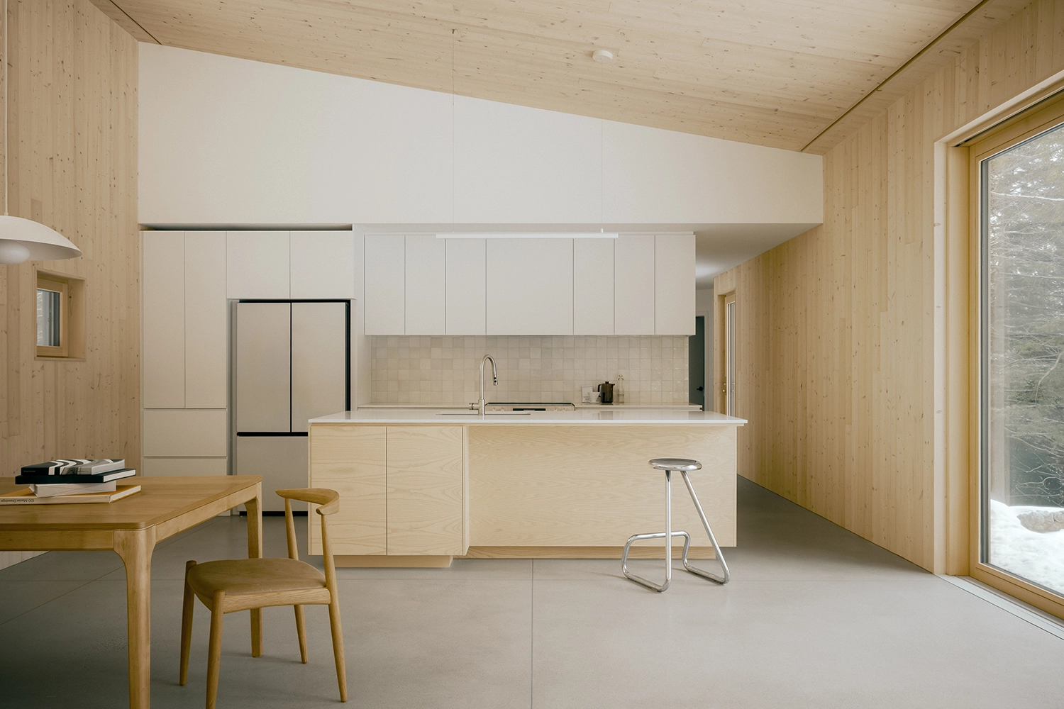 Modern kitchen with pale wood cabinetry, a white island, and a concrete floor.