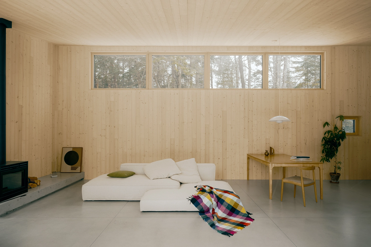 Wide view of a living space with a white modular sofa, light wood walls, and high clerestory windows.
