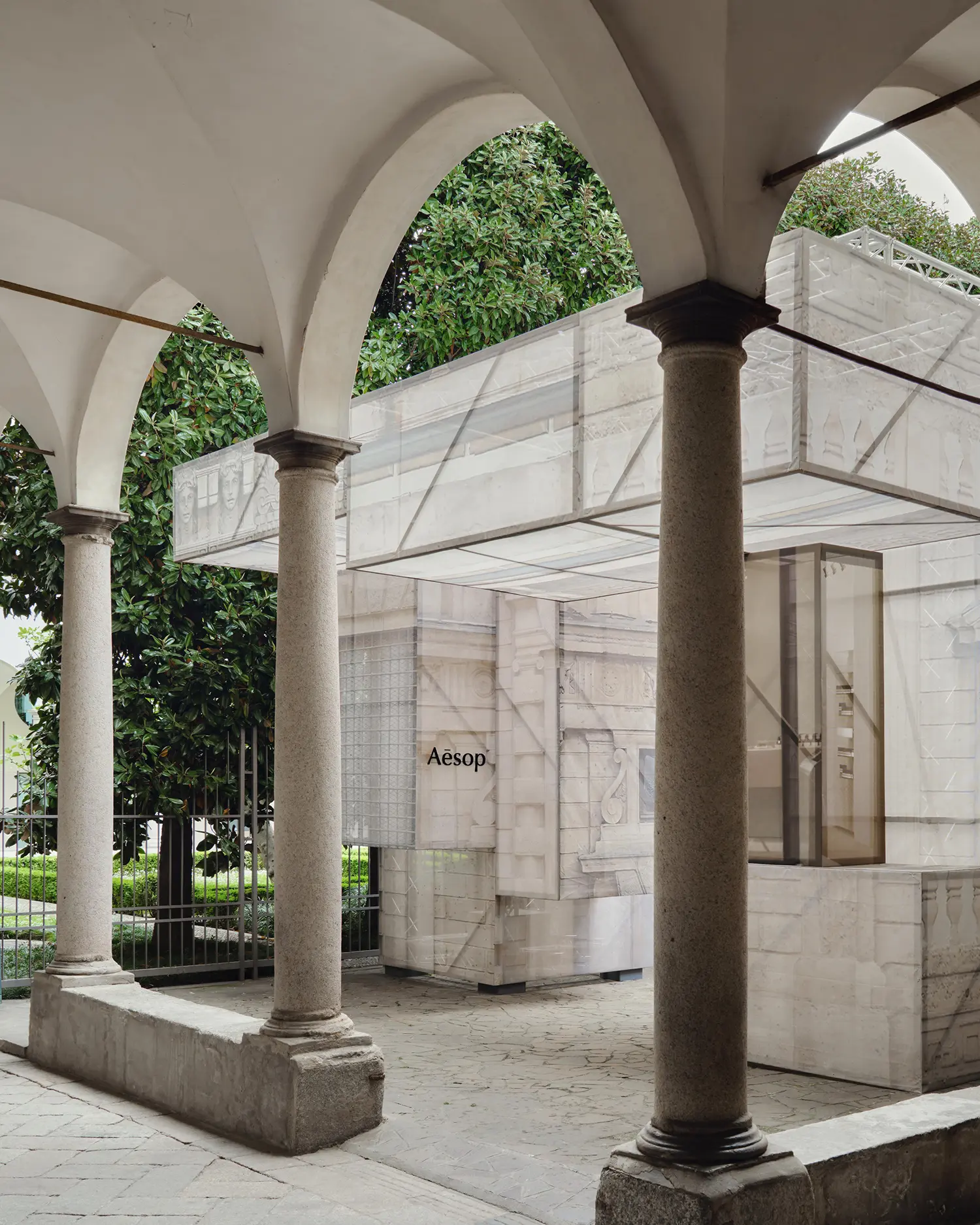 Detailed view of the translucent fabric structure framed by the historic arches of a Milanese cloister.