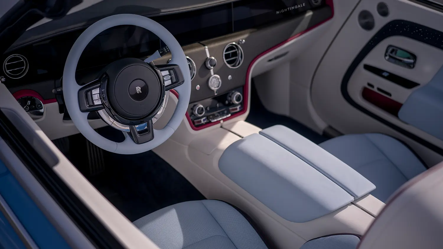 Close-up of the Project Nightingale interior featuring a light blue steering wheel and white leather "saddle" armrest.
