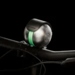 Close-up of the Škoda DuoBell mounted on a bicycle handlebar against a black background.