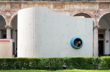 Close-up view of the curving grey textured facade with a prominent blue-ringed porthole.