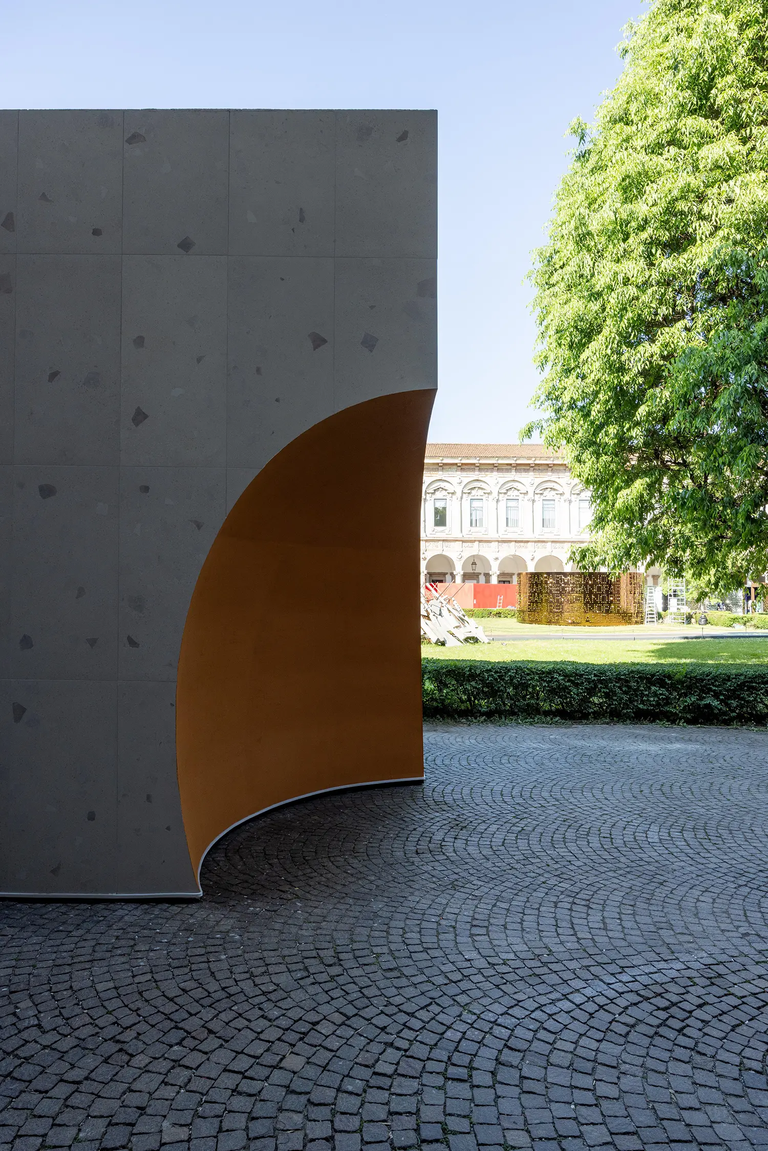 Curved terracotta-colored wall fragment framing the university courtyard.