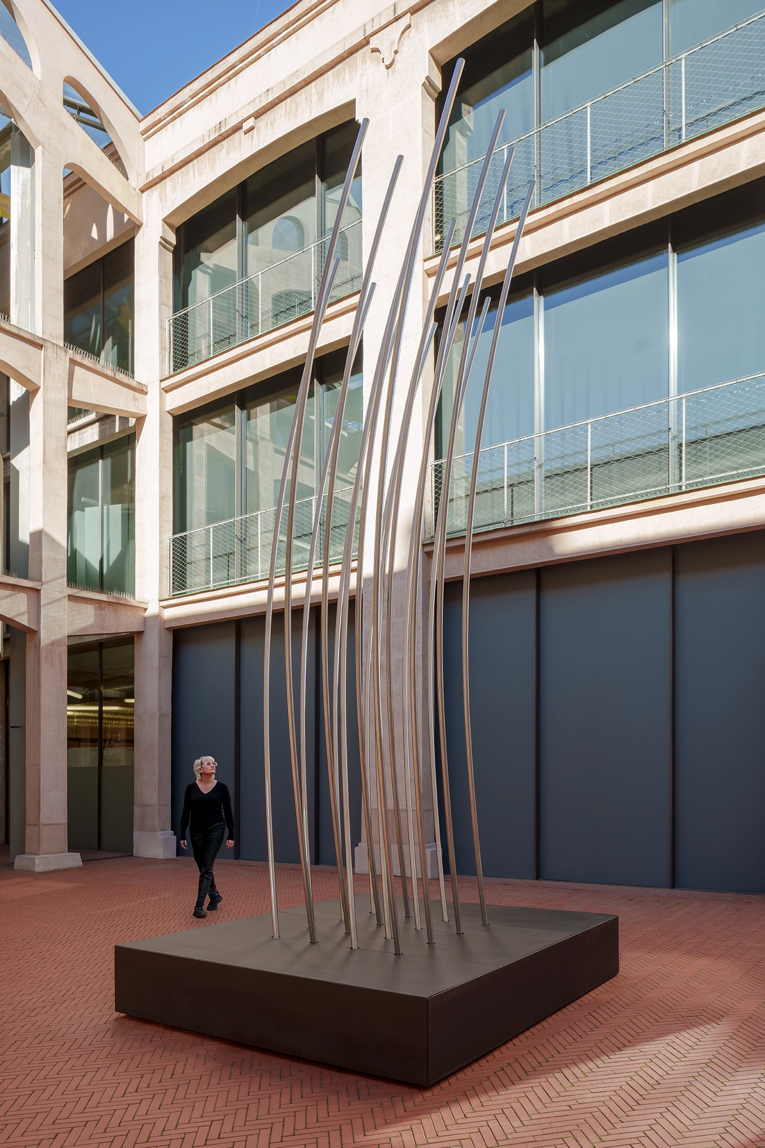 Side view of curved steel slats of DISLOCATION by SpY with a person walking past.