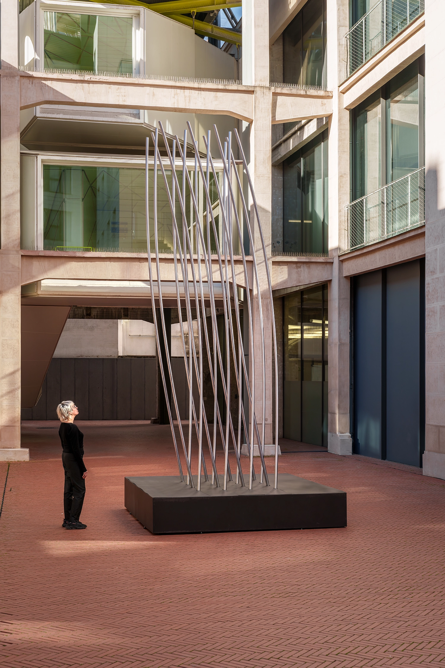 Vertical slats of SpY sculpture aligned in a rhythmic pattern against a building facade.