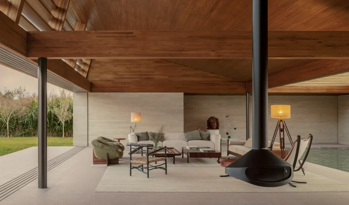Interior of a modern living room under a large timber ceiling with a black suspended fireplace and mid-century furniture.