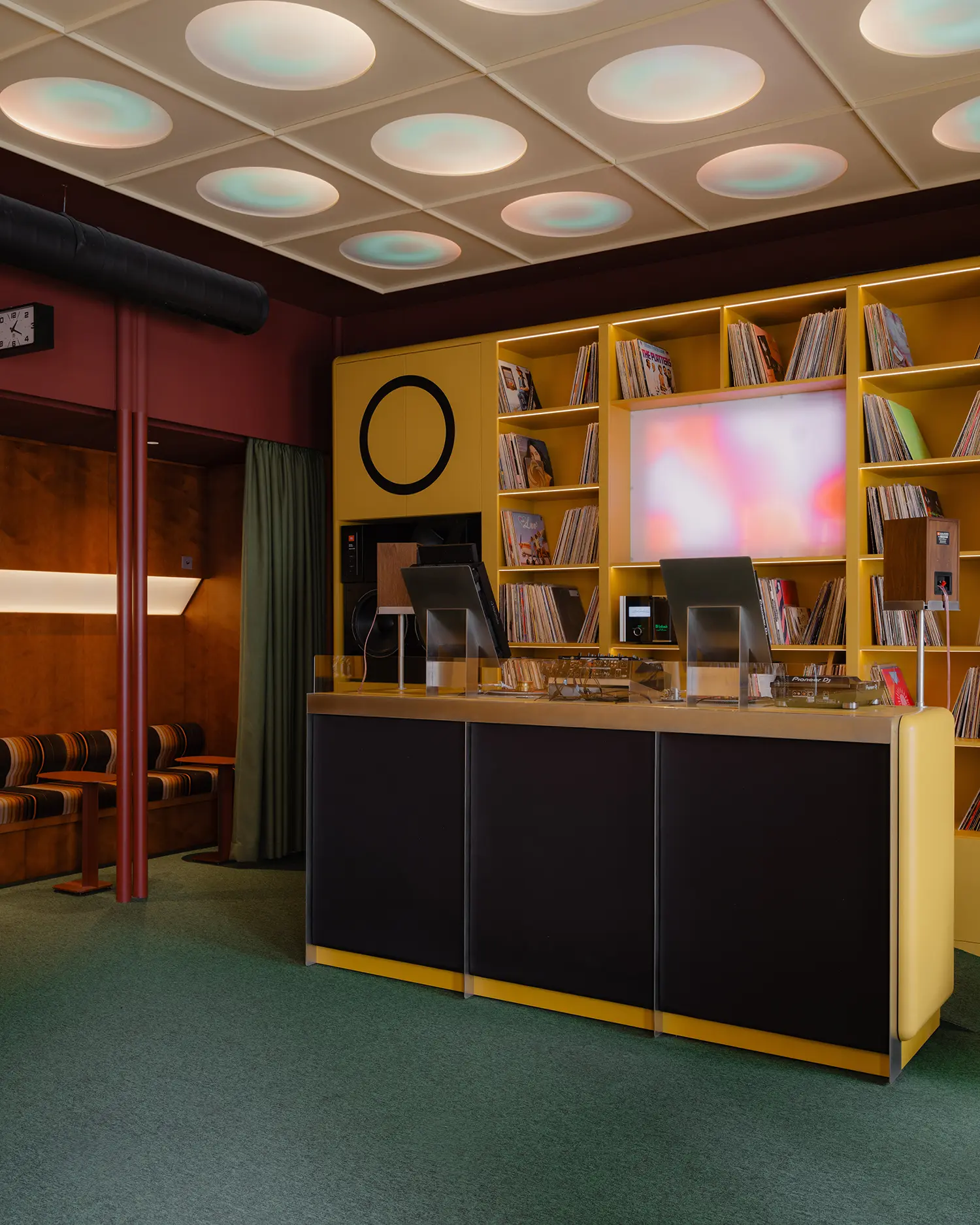 Close-up of the DJ booth at EJE Belgrade with custom yellow cabinetry and an illuminated ceiling.