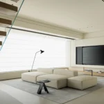 Minimalist living room with modular off-white sofa and floating wooden staircase.