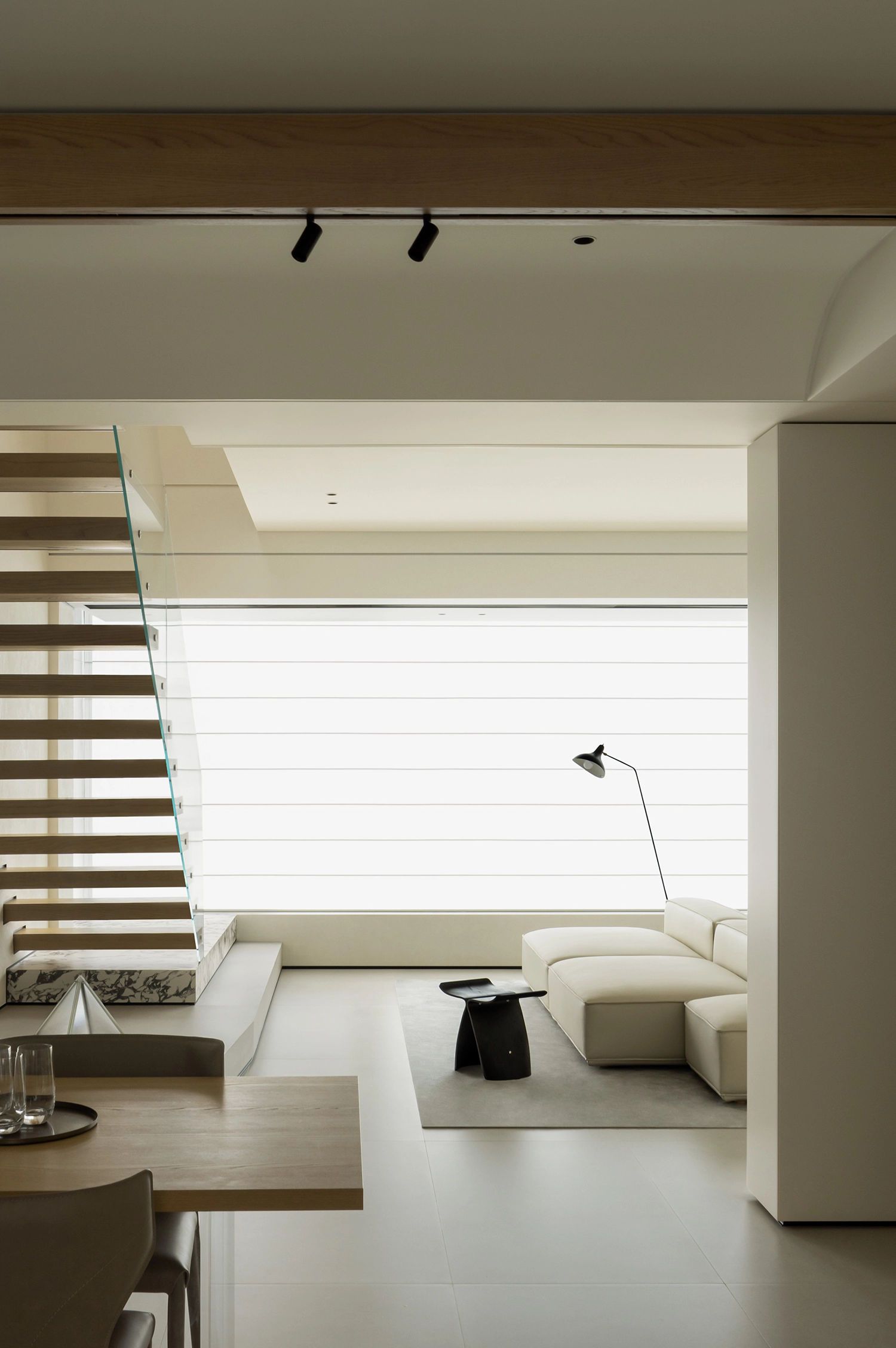 Vertical view of a minimalist interior with a floating staircase and open-plan dining area.