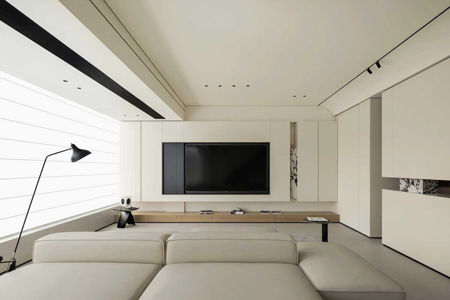 Integrated media wall with handleless cabinetry and built-in television in a minimalist home.