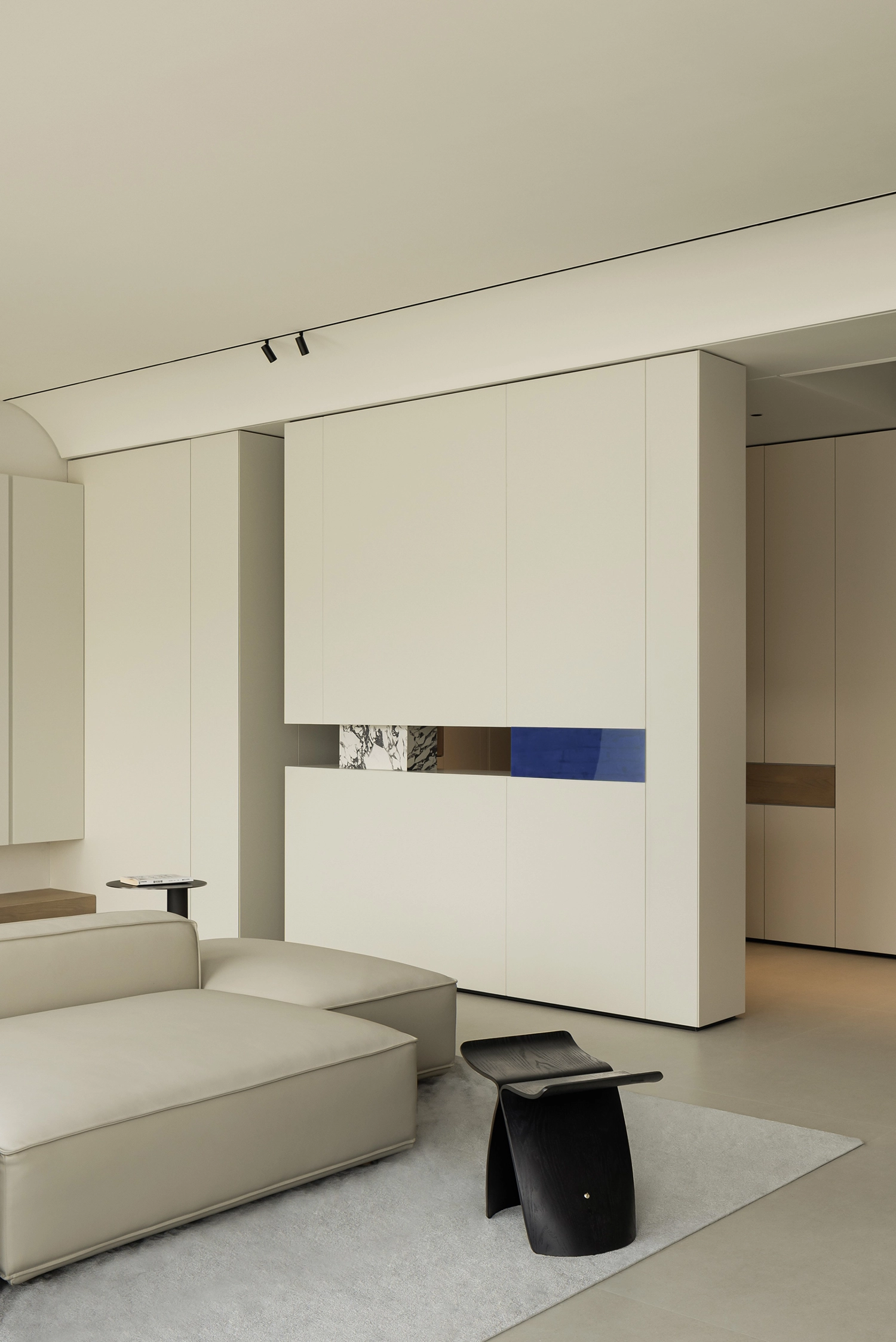 Close-up of minimalist white cabinetry with a marble and blue glass inset detail.